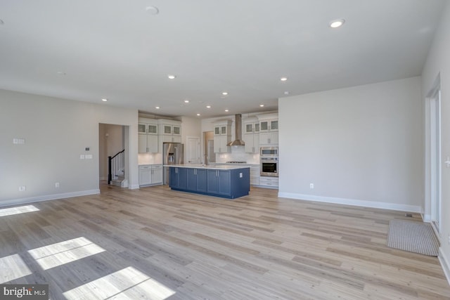 unfurnished living room with baseboards, stairway, light wood-type flooring, recessed lighting, and a sink