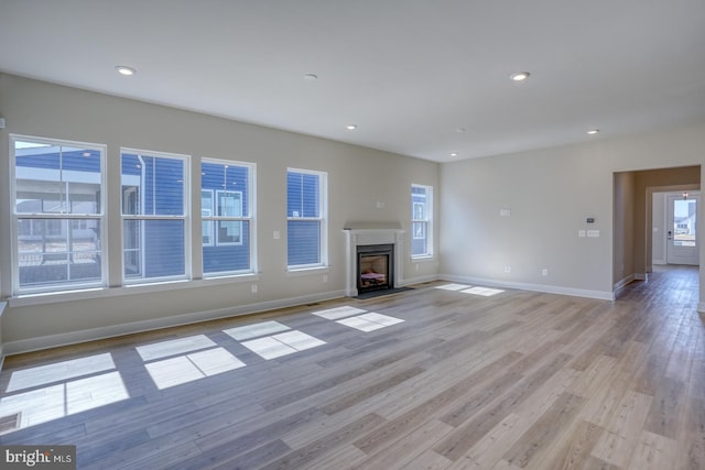 unfurnished living room featuring recessed lighting, light wood-type flooring, and a healthy amount of sunlight