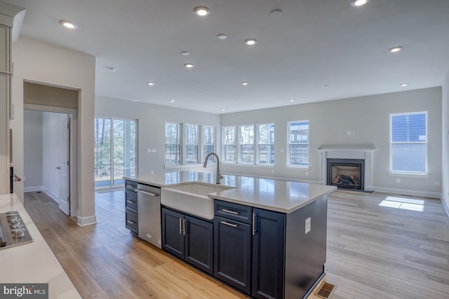 kitchen featuring light wood-type flooring, visible vents, a sink, stainless steel appliances, and light countertops