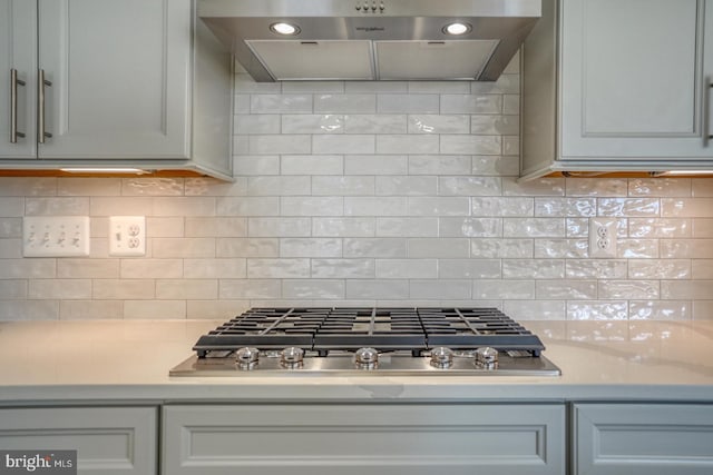 kitchen featuring under cabinet range hood, tasteful backsplash, recessed lighting, light countertops, and stainless steel gas cooktop