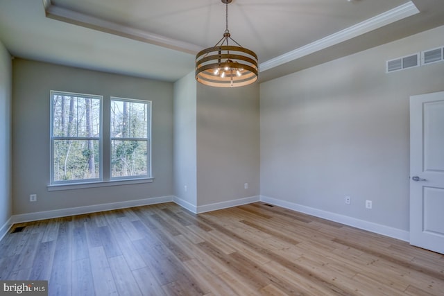 spare room featuring visible vents, baseboards, a chandelier, a tray ceiling, and wood finished floors