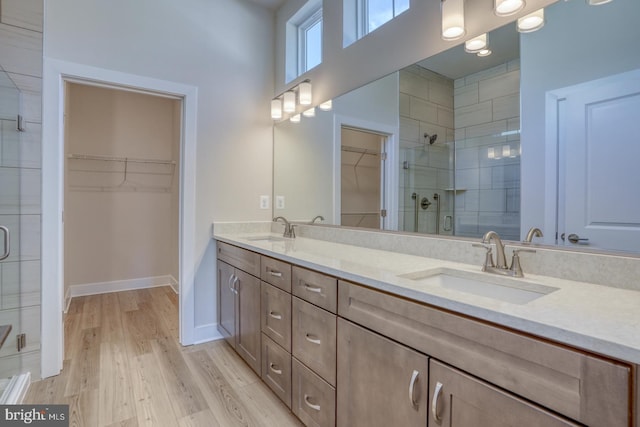 bathroom with double vanity, wood finished floors, a stall shower, and a sink