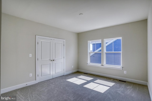 unfurnished bedroom with carpet, visible vents, a closet, and baseboards