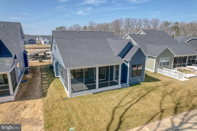 rear view of property featuring cooling unit, fence, roof with shingles, a yard, and a sunroom