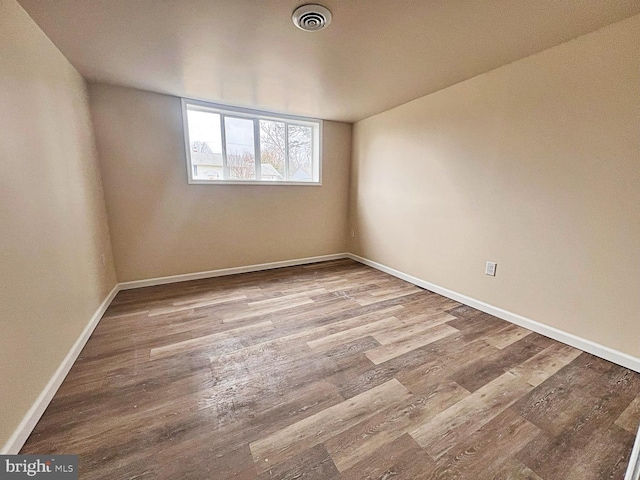 unfurnished room with visible vents, baseboards, and wood finished floors