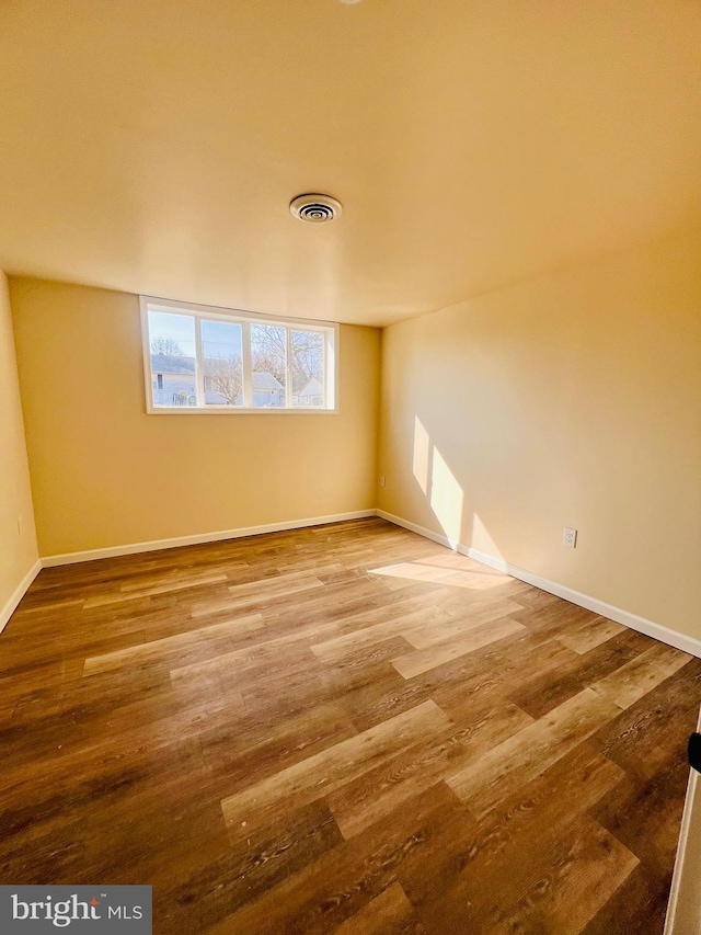 unfurnished room featuring wood finished floors, visible vents, and baseboards