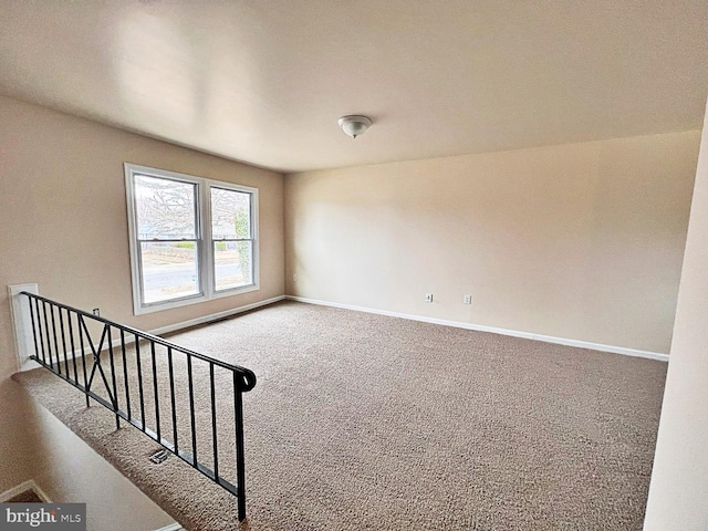 empty room featuring carpet and baseboards