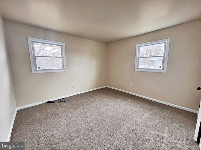 carpeted empty room featuring baseboards