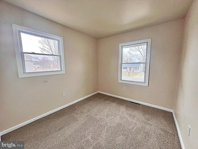 carpeted empty room featuring baseboards