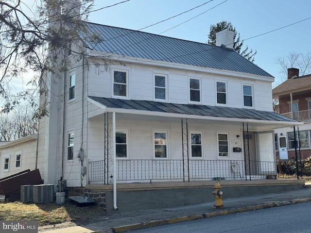 view of front of property featuring metal roof, a porch, a chimney, and a standing seam roof