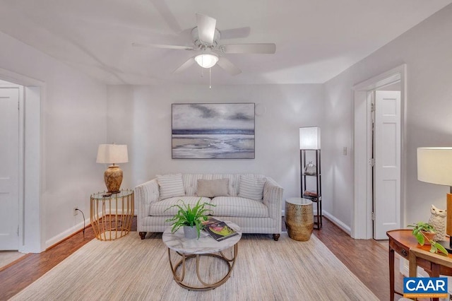 living room with ceiling fan, baseboards, and wood finished floors