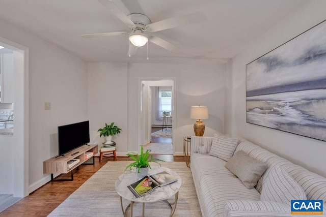 living area featuring baseboards, wood finished floors, and a ceiling fan