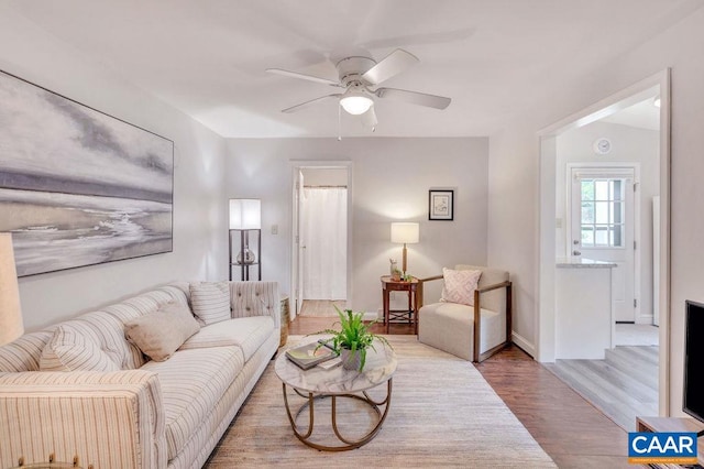 living area with baseboards, a ceiling fan, and wood finished floors