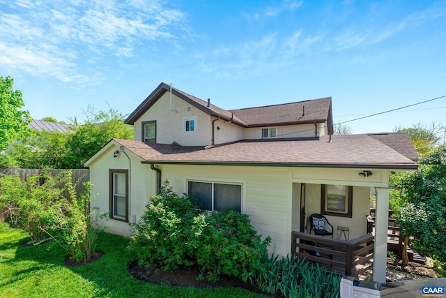 view of front of home featuring a shingled roof, fence, and stucco siding