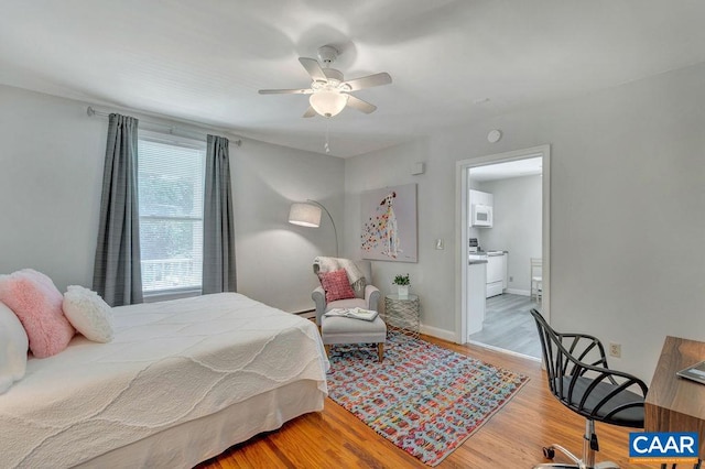 bedroom with ensuite bath, wood finished floors, baseboards, and ceiling fan