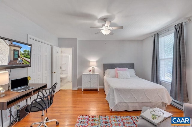 bedroom featuring a ceiling fan, wood finished floors, a closet, baseboards, and baseboard heating