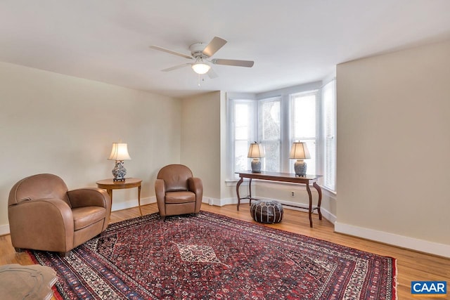 sitting room featuring baseboards, wood finished floors, and a ceiling fan