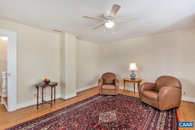 living area with ceiling fan, visible vents, baseboards, and wood finished floors