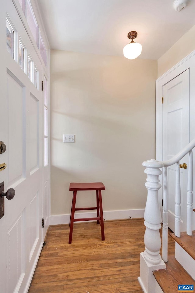 foyer entrance with light wood-style flooring and baseboards