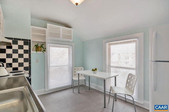 kitchen featuring decorative backsplash, white appliances, plenty of natural light, and lofted ceiling