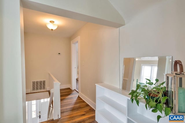 hall featuring visible vents, baseboards, and hardwood / wood-style floors