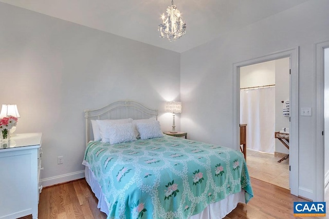 bedroom with baseboards, an inviting chandelier, and wood finished floors