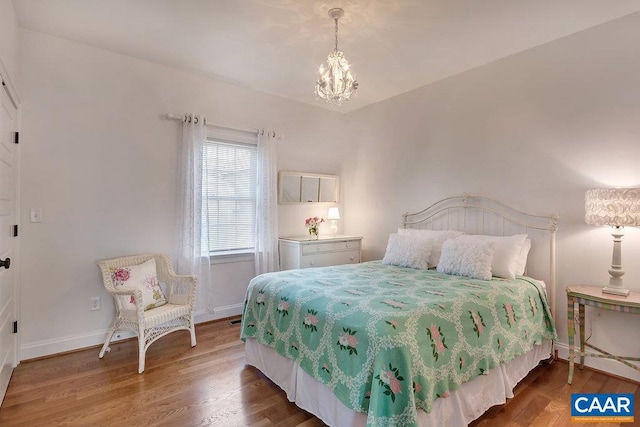 bedroom with baseboards, an inviting chandelier, and wood finished floors