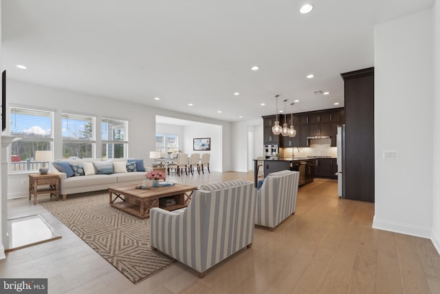 living room with a wealth of natural light, recessed lighting, baseboards, and light wood-style floors