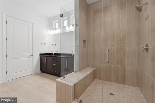 bathroom with a sink, double vanity, wood finished floors, and a shower stall