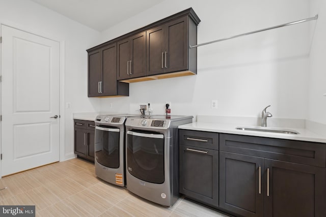 clothes washing area featuring washing machine and clothes dryer, cabinet space, and a sink