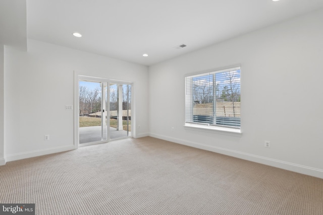 carpeted spare room with baseboards, visible vents, and a wealth of natural light