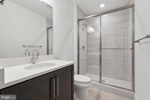 bathroom with recessed lighting, toilet, a stall shower, and vanity