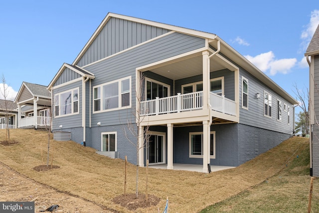 rear view of house with a patio area, board and batten siding, and brick siding