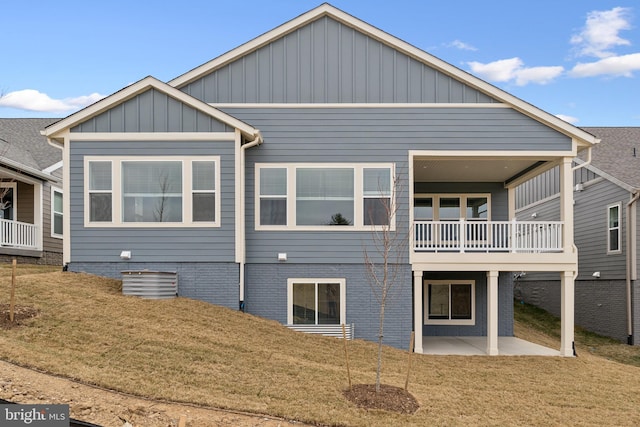 back of property featuring a yard, board and batten siding, and a patio