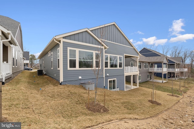 back of property featuring board and batten siding, central AC, and a yard