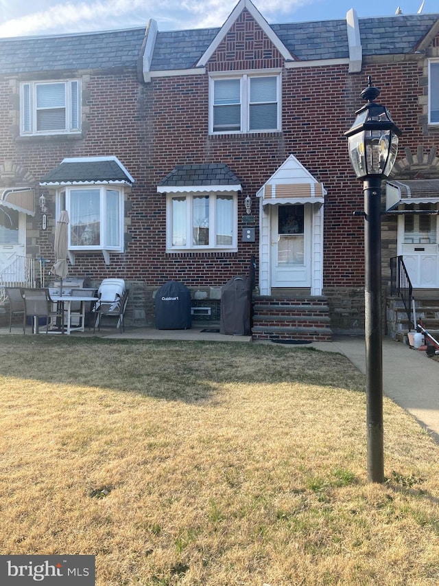 view of property with brick siding, entry steps, and a front yard