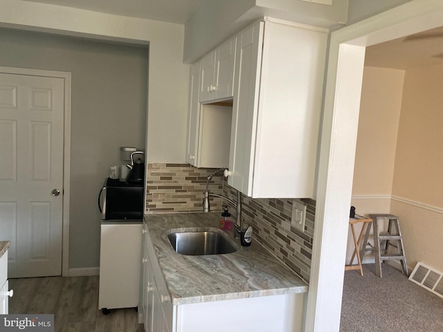 kitchen featuring visible vents, light stone countertops, white cabinetry, and a sink