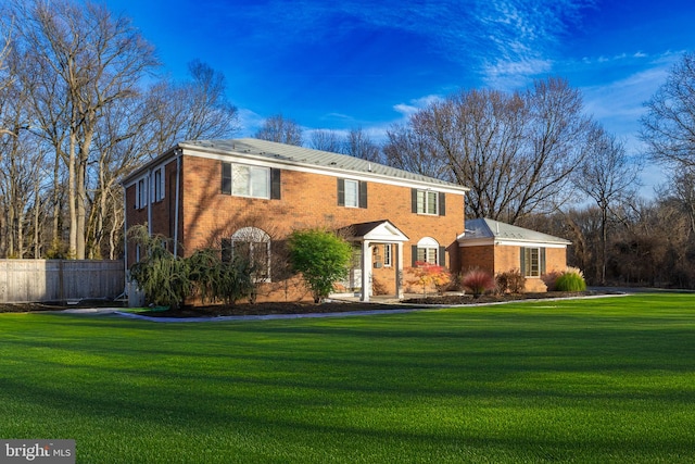 view of front of home featuring brick siding, a front lawn, and fence