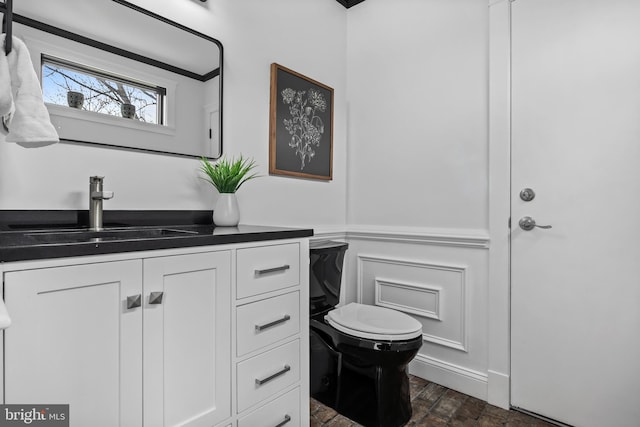 bathroom with toilet, vanity, and a decorative wall