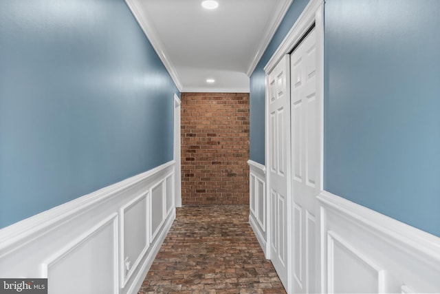 corridor with crown molding, a wainscoted wall, recessed lighting, brick floor, and a decorative wall