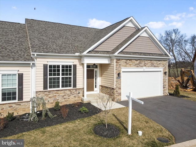 craftsman-style house with a garage, stone siding, driveway, and a shingled roof