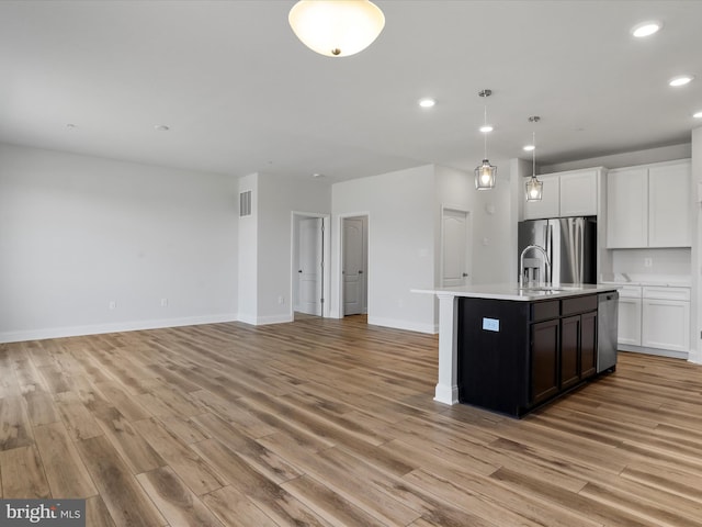 kitchen featuring light wood-style floors, light countertops, stainless steel refrigerator with ice dispenser, and a sink