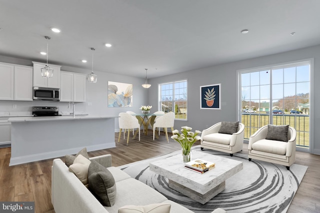 living area featuring recessed lighting, light wood-style floors, and baseboards