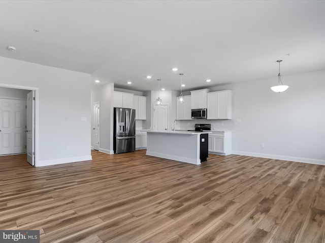 kitchen with a sink, open floor plan, stainless steel appliances, light wood-style floors, and light countertops