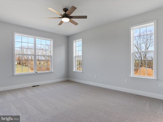 empty room featuring light carpet, visible vents, baseboards, and ceiling fan