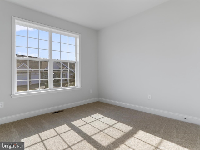 carpeted empty room featuring visible vents and baseboards