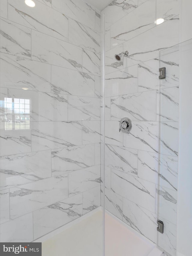 bathroom featuring a marble finish shower