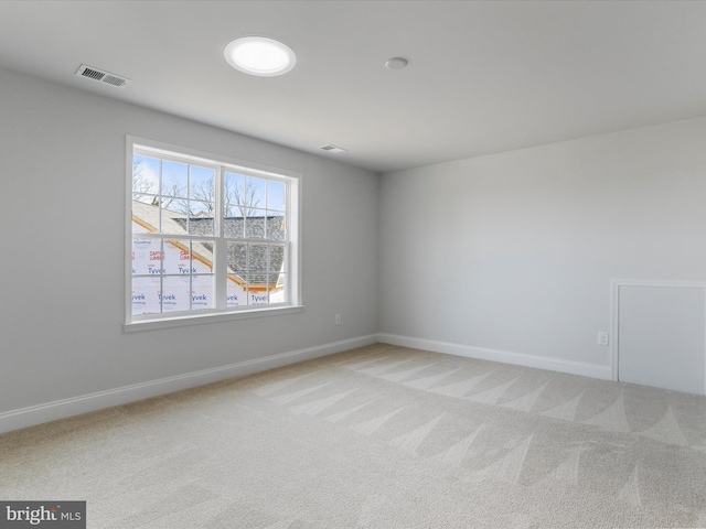 spare room featuring visible vents, light colored carpet, and baseboards