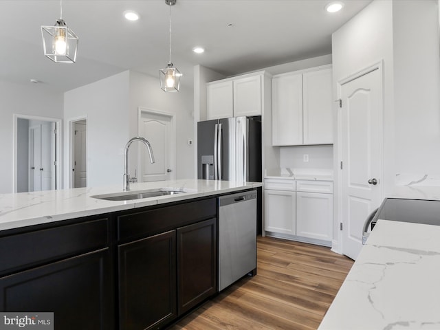 kitchen with pendant lighting, stainless steel appliances, light wood-style floors, white cabinetry, and a sink