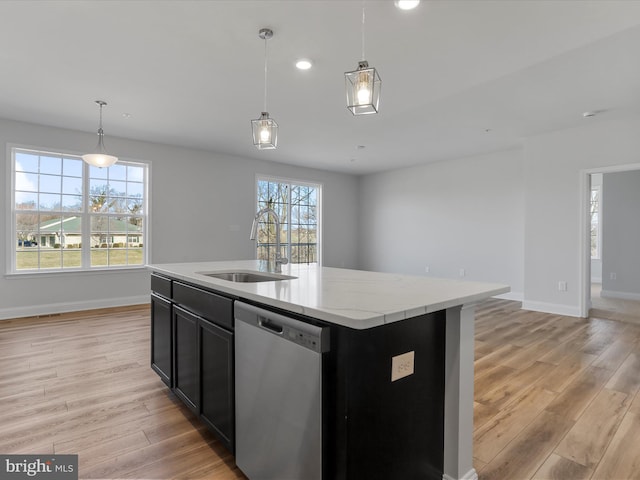 kitchen with a sink, open floor plan, dark cabinetry, light wood finished floors, and dishwasher